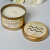 Candle in a metal container labeled 'Cherry Blossom Aquarius Zodiac' with a decorative lid featuring an Aquarius symbol.