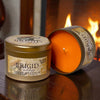 Brigid candle with lit candle and packaging in front of a fireplace