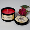 Femme Fatale candle in a black tin with a red candle inside, next to a red rose on a light background.