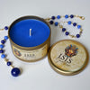 Blue candle in a tin labeled 'Isis' with a necklace on a white background
