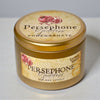 Persephone Goddess Pomegranate candle in a tin with a matching label on a light background