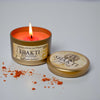Shakti Goddess candle in a tin with a lit candle on a gray background