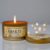Shakti Goddess sandalwood saffron candle in a metallic tin with a blurred background