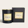 A matte black soy wax candle jar with a gold-toned rim and a beige label reading 'Virgo Zodiac Soy Wax Candle,' shown next to a matching black box with the same label on a light warm-gray background.